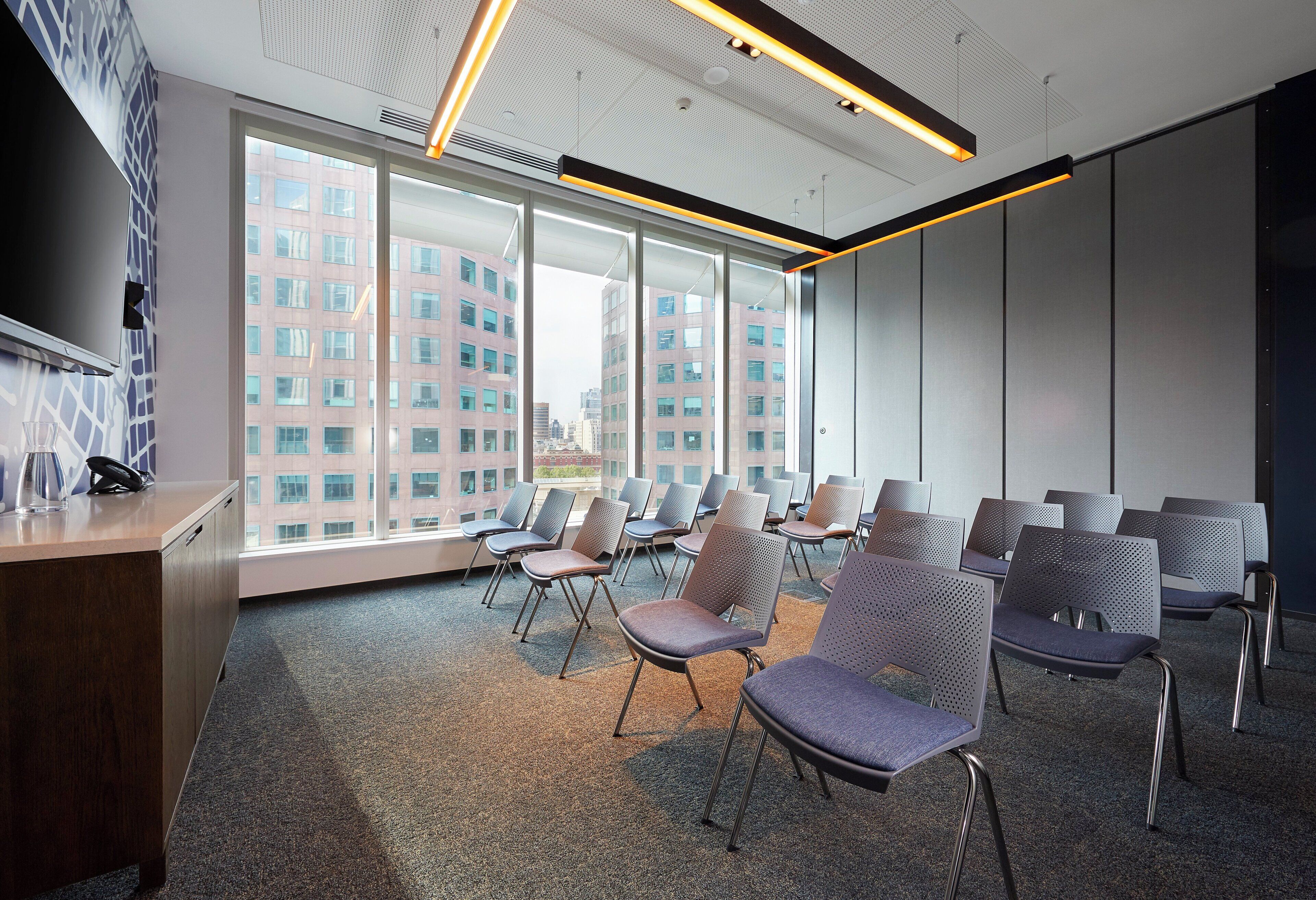 Une salle de conférence au design moderne, dotée d’une grande fenêtre offrant une vue sur la ville, d’un bureau avec un téléphone et de plusieurs chaises disposées pour les réunions.