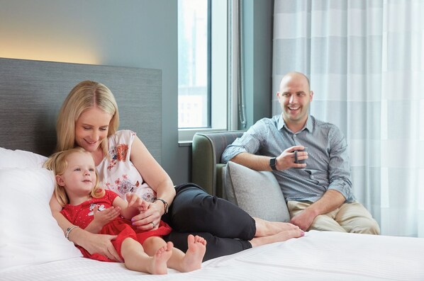 A hotel room with a bed, a window with curtains, and a view of the city. - Holiday Inn Express Melbourne Southbank by IHG (Southbank)