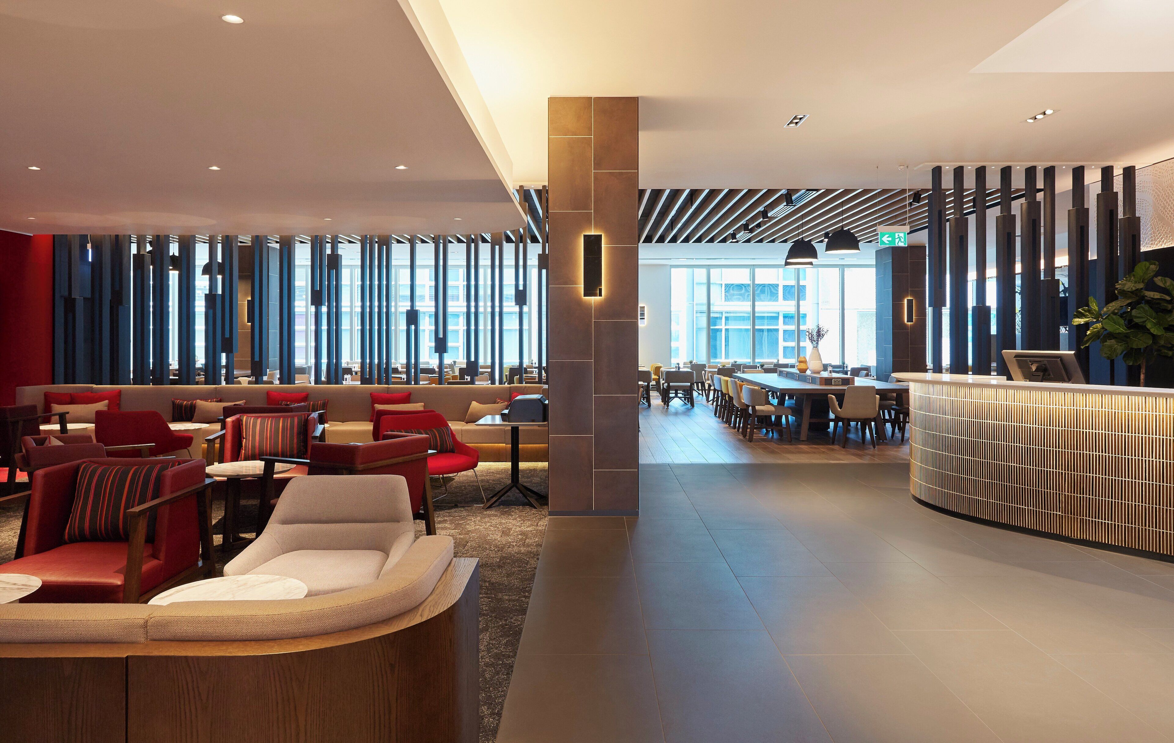 A modern hotel lobby with seating areas, a reception desk, and large windows allowing natural light.