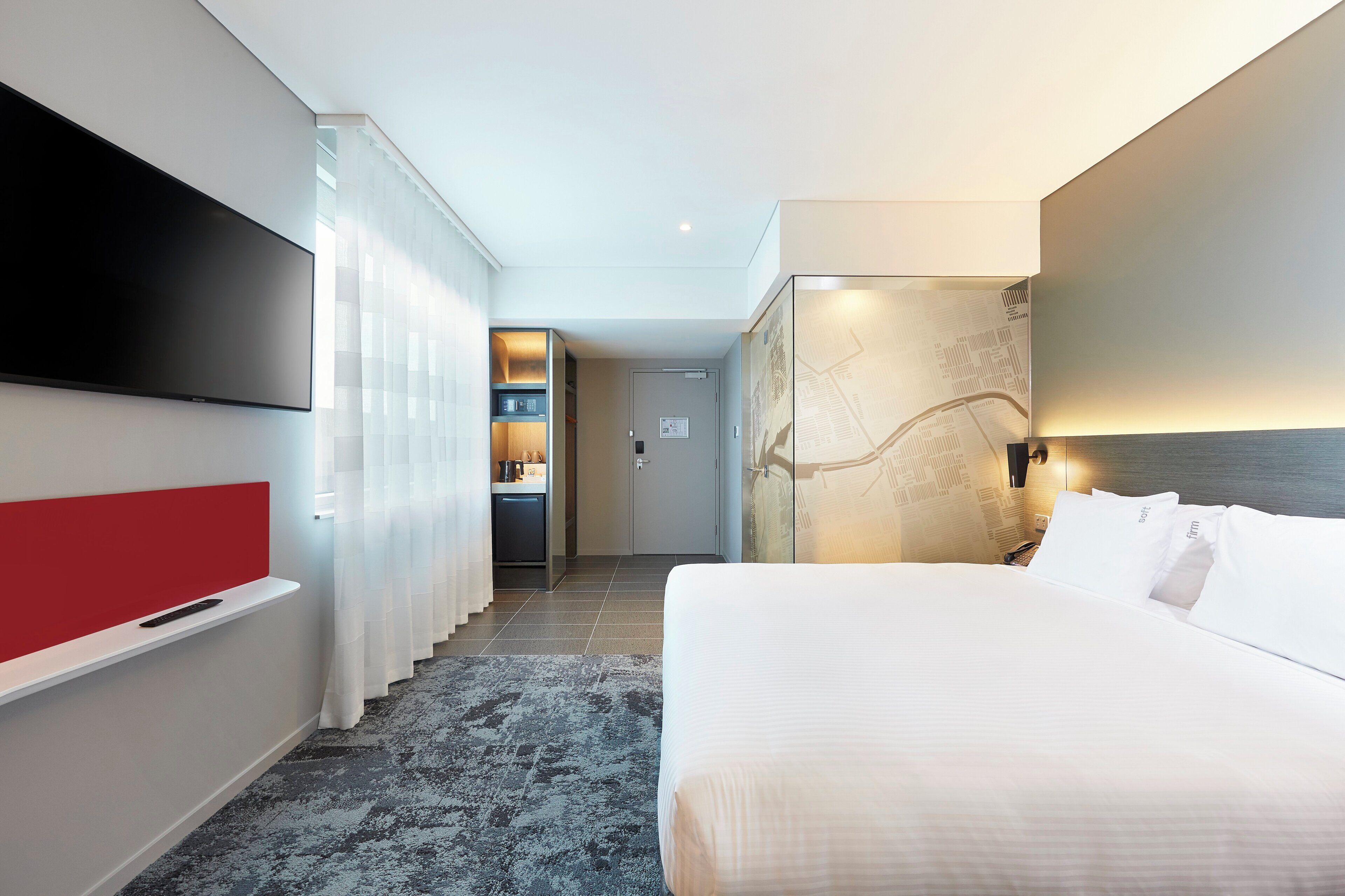 A hotel room with a bed, a TV, a desk, and a bathroom.
