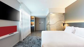 A hotel room with a bed, a TV, a desk, and a bathroom.