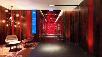 A hotel corridor with a reception desk, seating area, and a digital directory.
