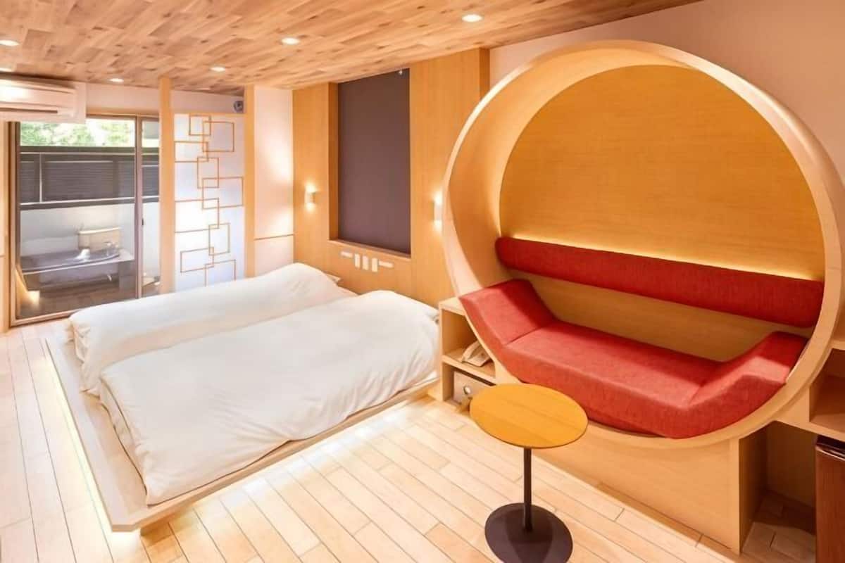 Une chambre à coucher comprenant un lit, un espace salon circulaire, une petite table et une fenêtre.