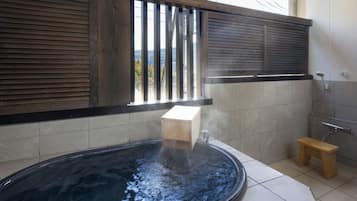 Relax in a heated hot tub, surrounded by a wooden bench and stool.