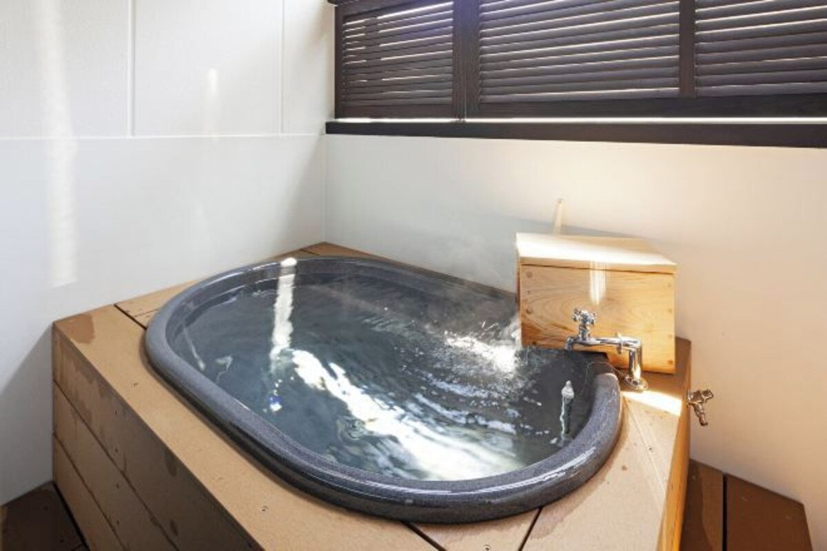 Ein Badezimmer mit einer freistehenden Badewanne, einem Holzschrank und einem Fenster mit Jalousien.