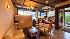 Un intérieur moderne avec un espace salon, un comptoir en bois et de grandes fenêtres donnant sur un paysage verdoyant.