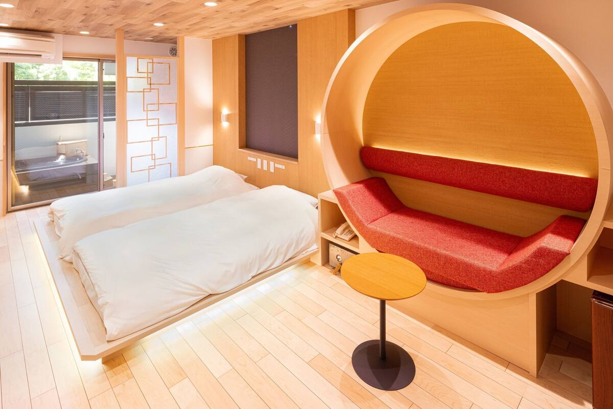 Une chambre moderne avec un grand lit, un coin salon circulaire et une petite table.