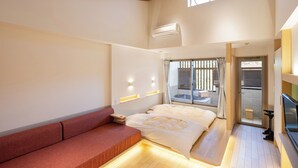Une chambre d’hôtel moderne avec un plafond en bois, un grand lit, un canapé rouge et un téléviseur.