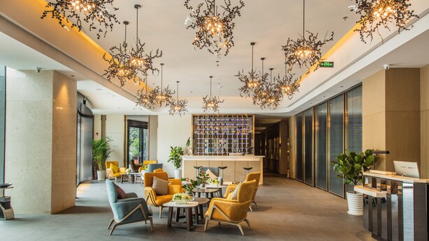 Um lobby moderno com balcão de recepção, área de estar e iluminação decorativa.