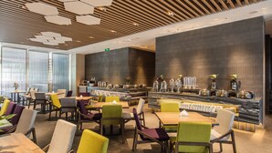 Um restaurante moderno com área de bar, teto de madeira e grandes janelas.