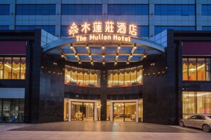 The exterior of The Mulian Hotel with a modern glass facade and illuminated signage. - The Mulian Hotel of Bantian Shenzhen (Shenzhen)