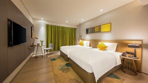 Quarto de hotel moderno com uma cama grande, uma escrivaninha, uma cadeira e uma televisão.