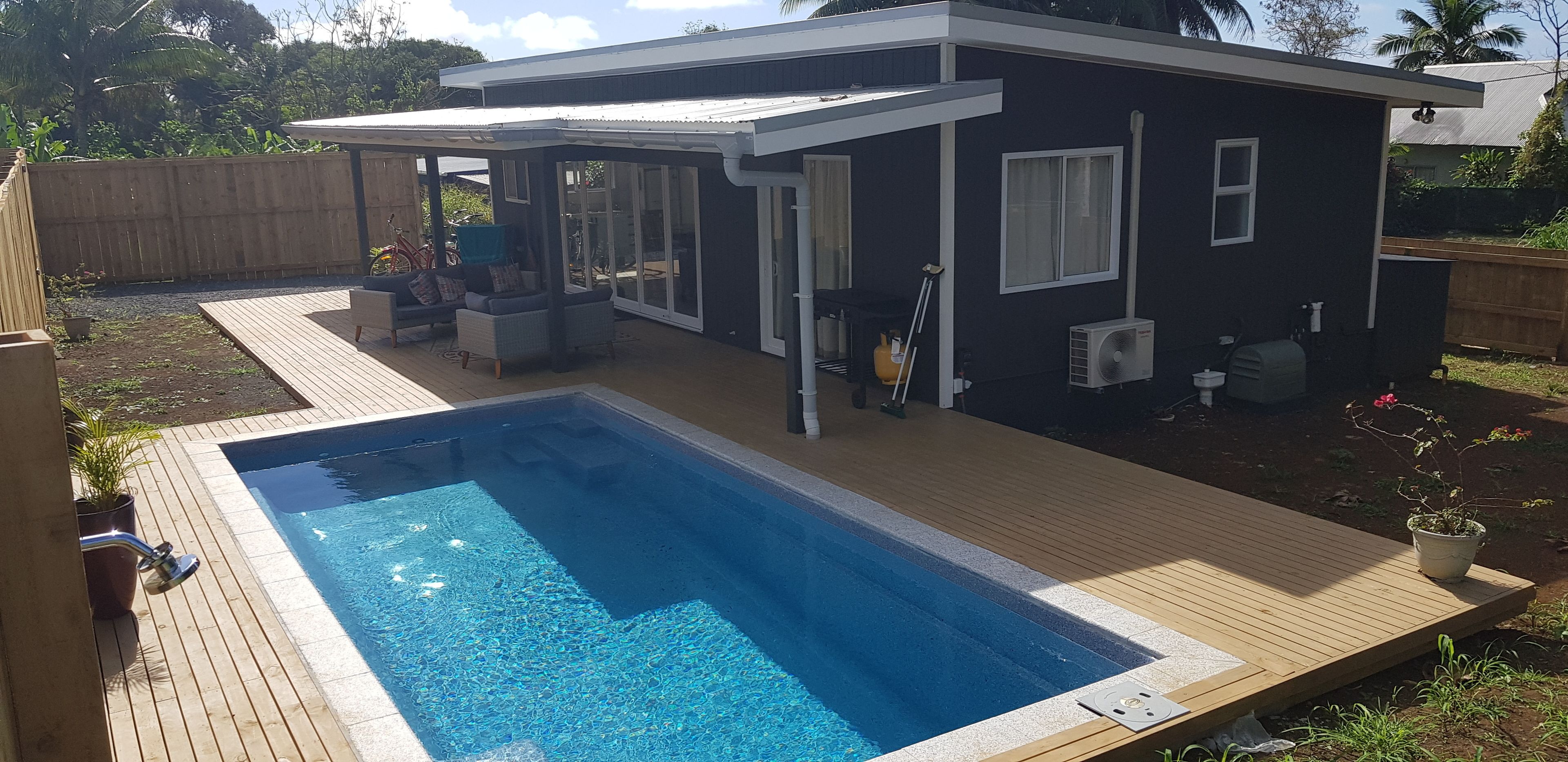 Una casa moderna con piscina, patio y zona de estar al aire libre techada.