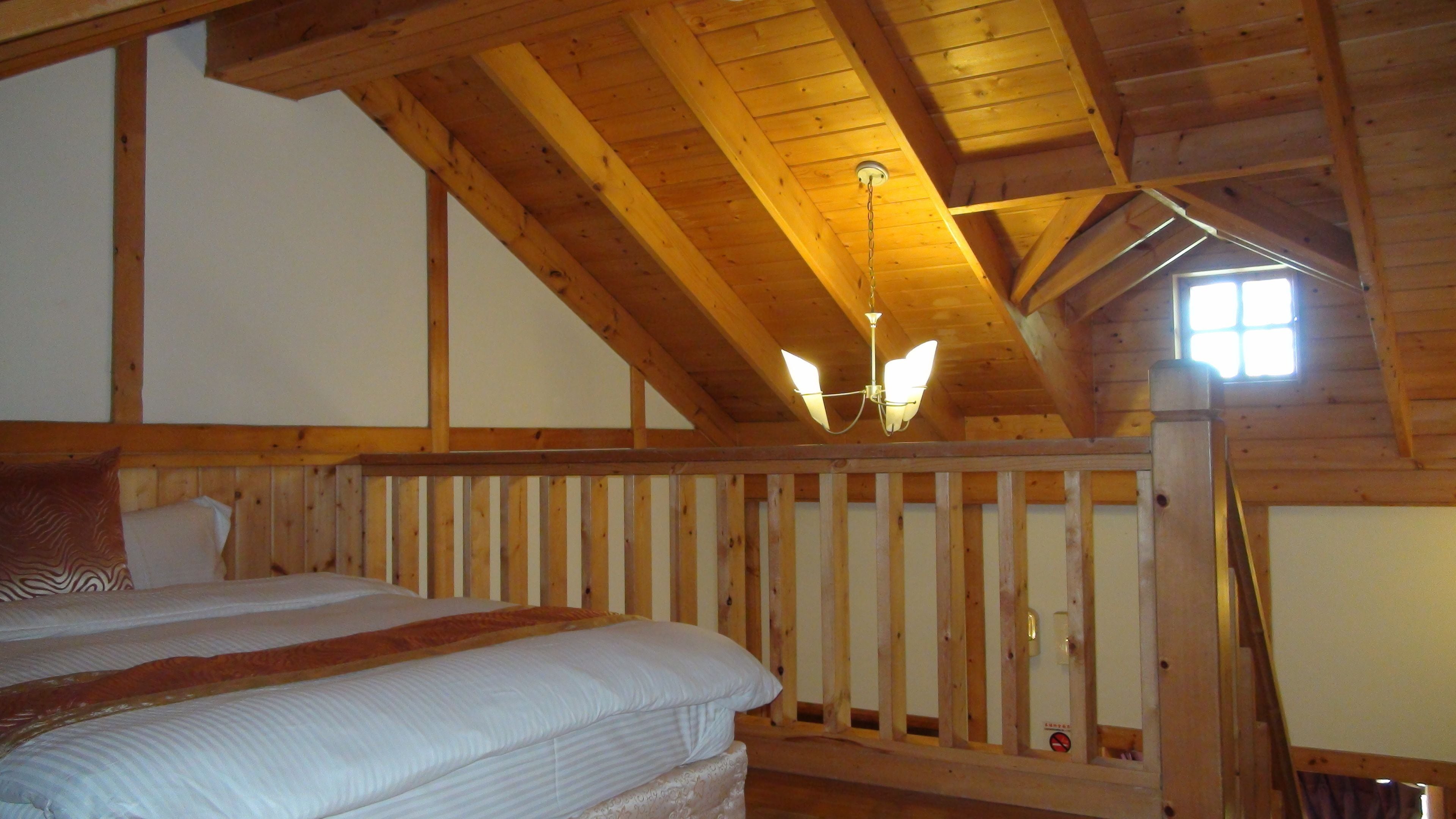 Un dormitorio con techo de madera, una cama con ropa blanca y una mesita de noche.