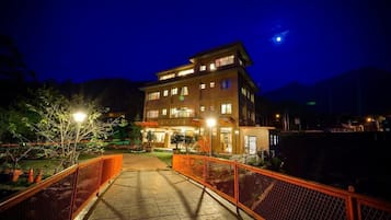 A multi-story hotel with a well-lit entrance and a fenced pathway leading to the building.