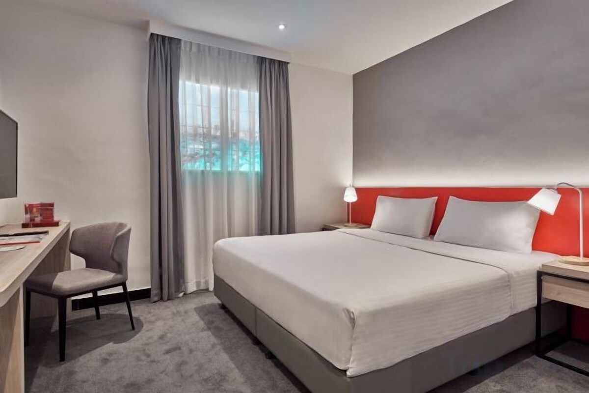 Une chambre d’hôtel avec un lit, un bureau, une chaise et une vue sur une piscine.