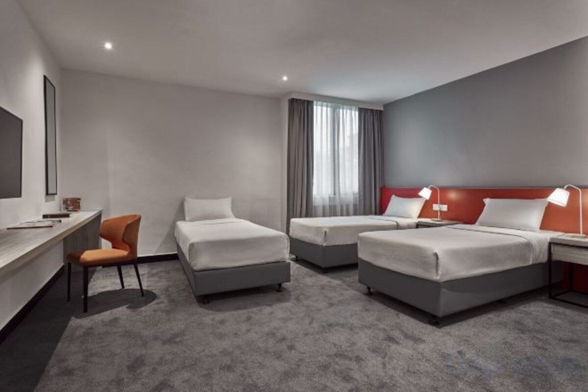Een hotelkamer met twee bedden, een bureau en een stoel.