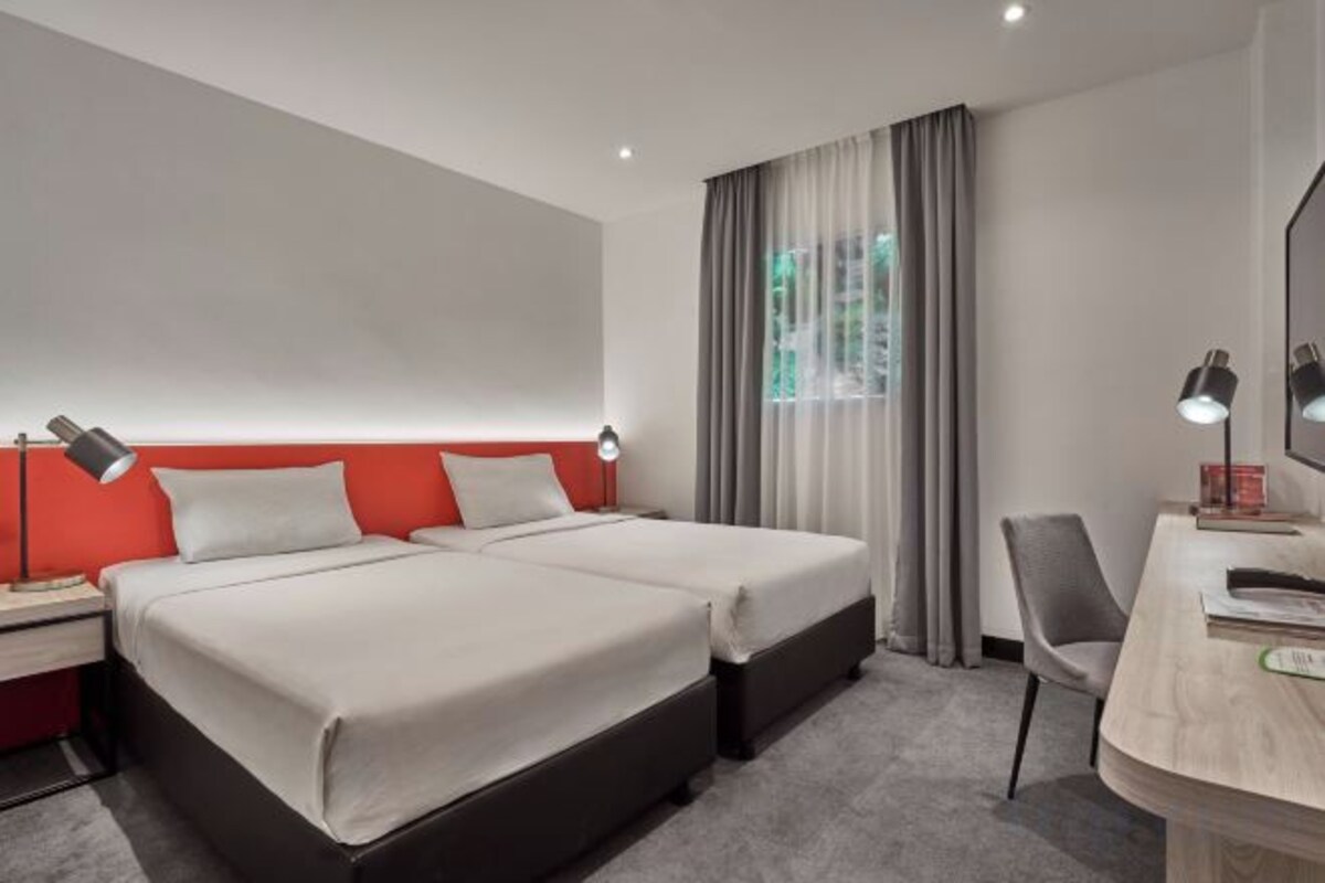Een hotelkamer met twee bedden, een bureau en een stoel.