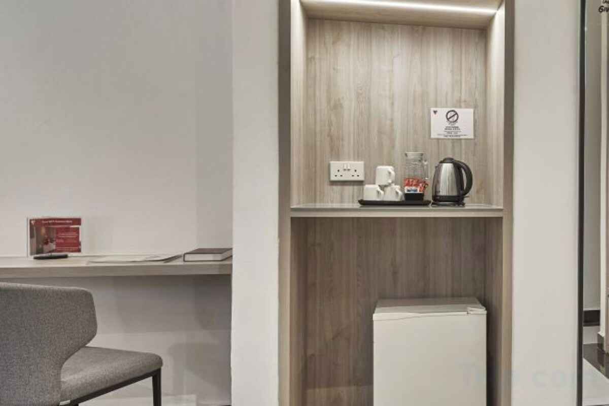 Een kitchenette met een koffiezetapparaat, waterkoker en een kleine koelkast.