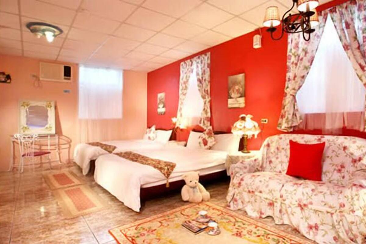 Une chambre d’hôtel avec un lit, un canapé, une chaise, une table et une fenêtre avec des rideaux.