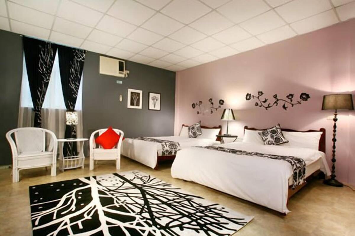 Une chambre avec deux lits, un bureau, des chaises et un grand tapis.