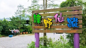 A wooden sign with colorful text in a natural setting. - Green Ozland B&B (Dongshan)