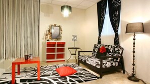 A living room with a sofa, a red table, a patterned rug, a lamp, and a mirror. - Green Ozland B&B (Dongshan)