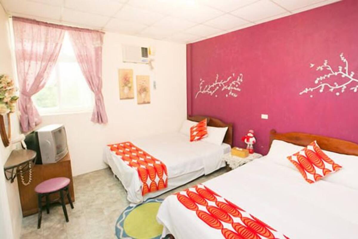 Une chambre d’hôtel avec deux lits, une télévision et un bureau.