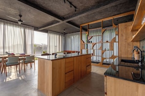 A modern kitchen with a central island, wooden cabinetry, and a built-in sink. - Balian Surf Villas (Selemadeg)