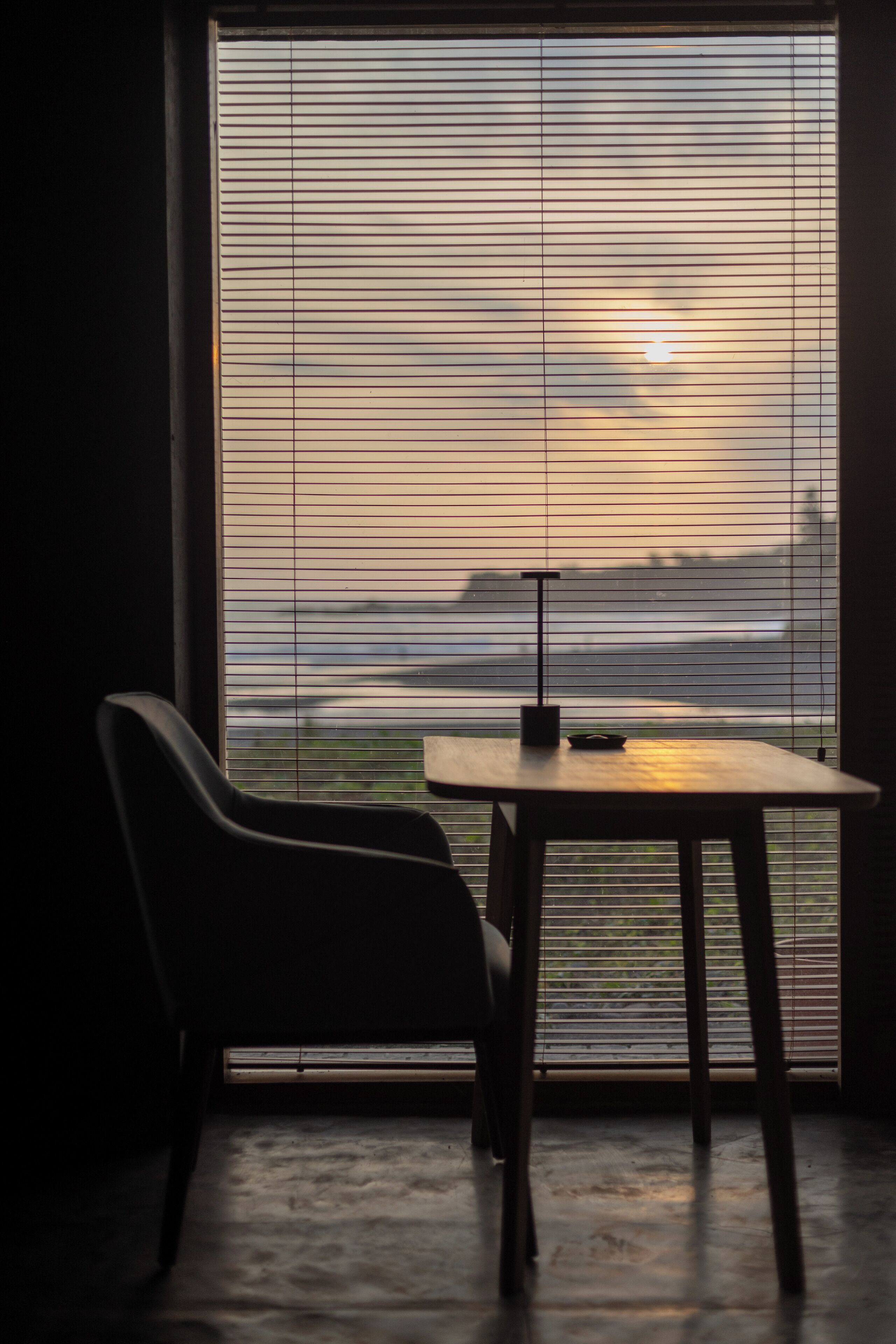 A room with a large window, a table, and a chair.