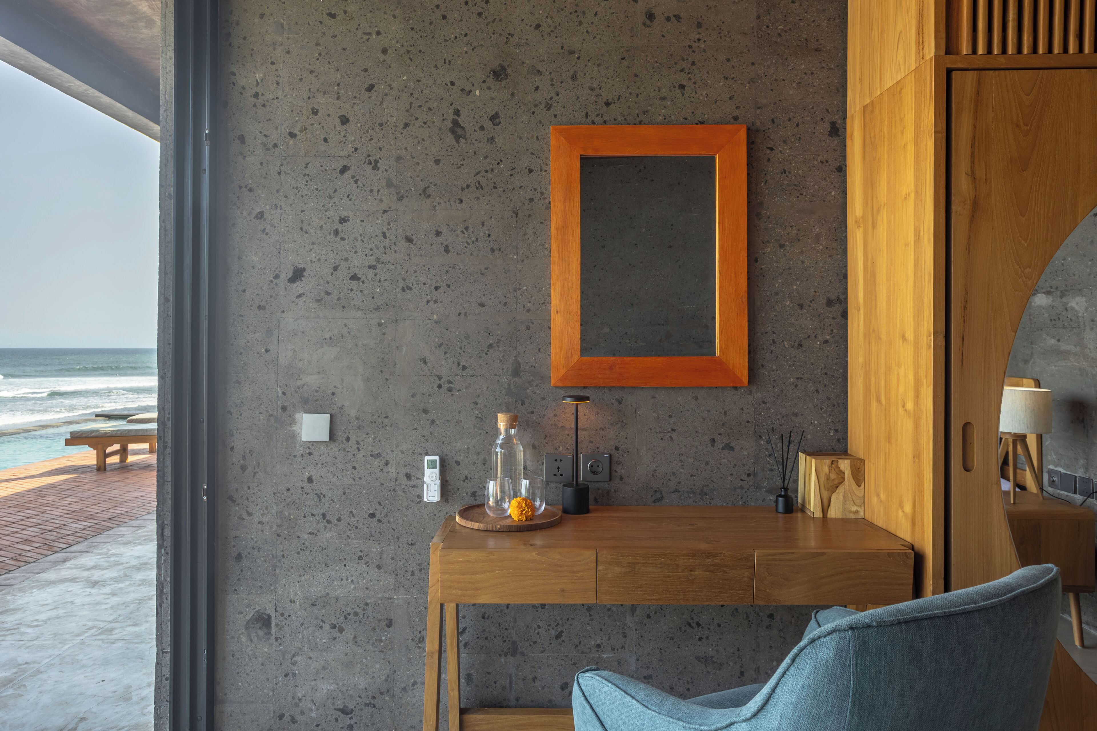 A modern room with a wooden desk, a chair, a framed picture on the wall, and a view of the ocean.