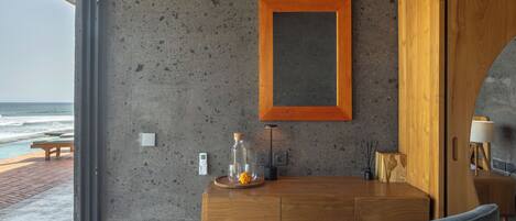 A modern room with a wooden desk, a chair, a framed picture on the wall, and a view of the ocean.