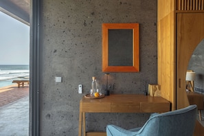 A modern room with a wooden desk, a chair, a framed picture on the wall, and a view of the ocean. - Balian Surf Villas (Selemadeg)