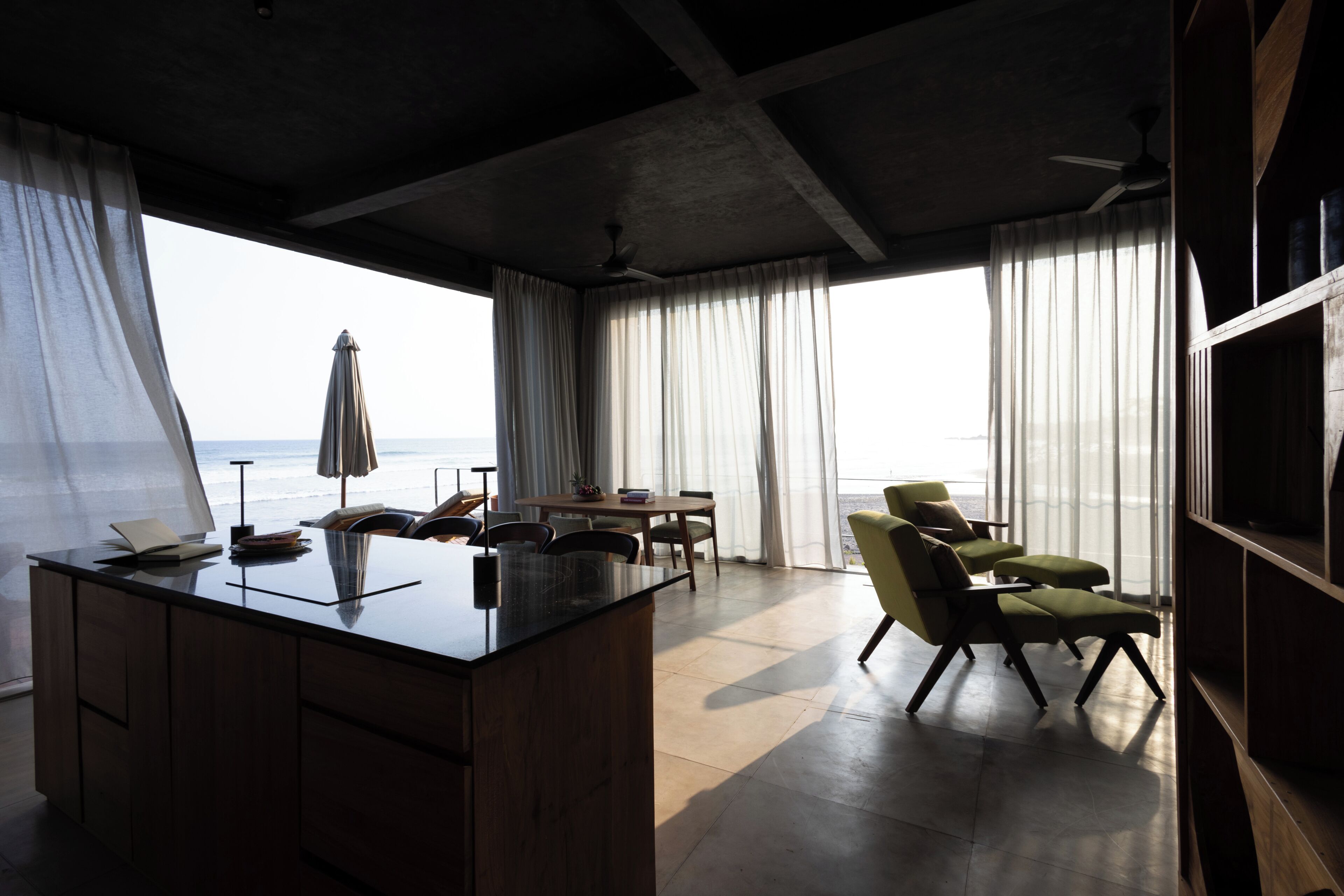 Una habitación moderna con un ventanal grande, un comedor y una zona de estar con vistas al mar.