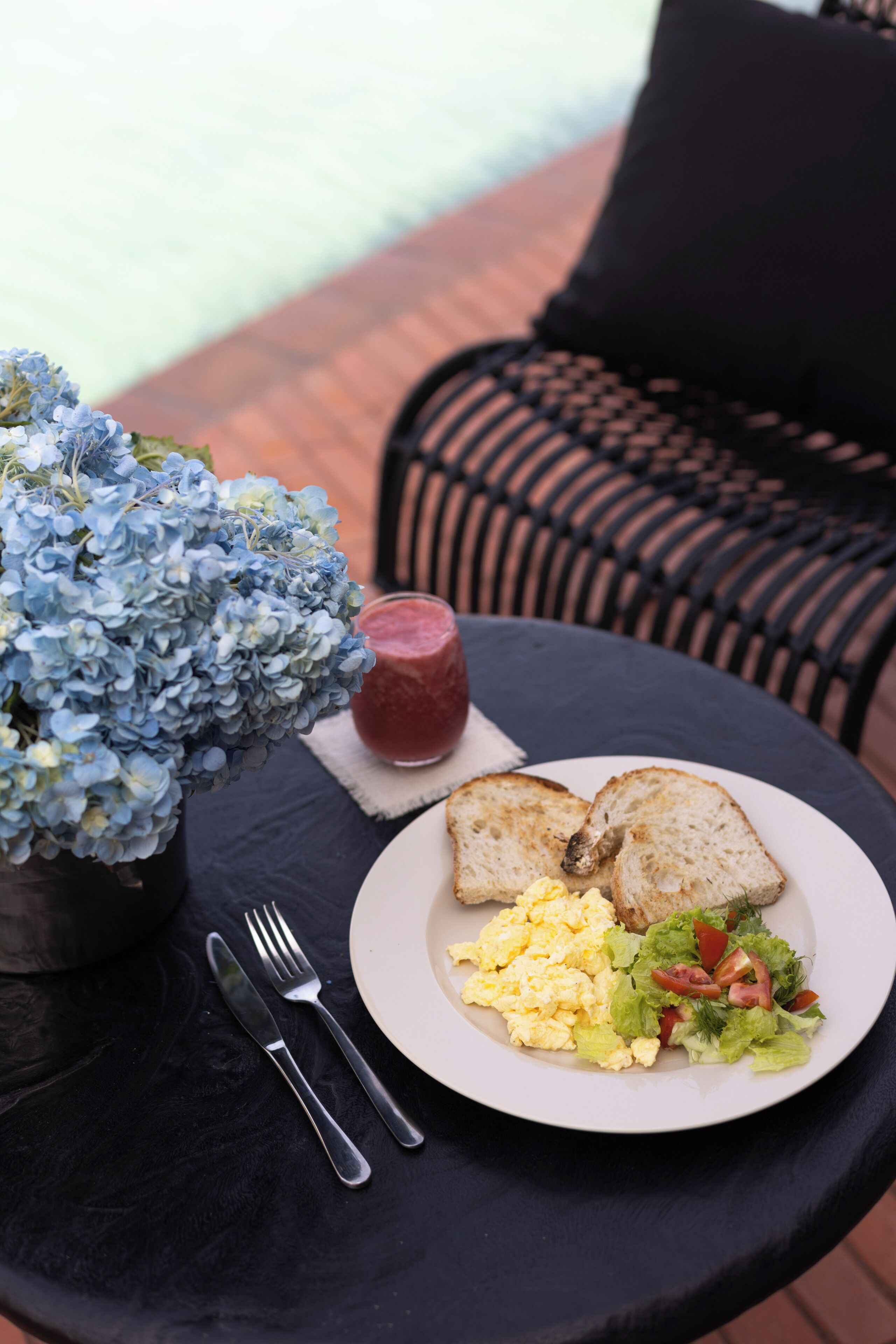 Una mesa de comedor con un plato de comida, un vaso de jugo y un florero con flores.