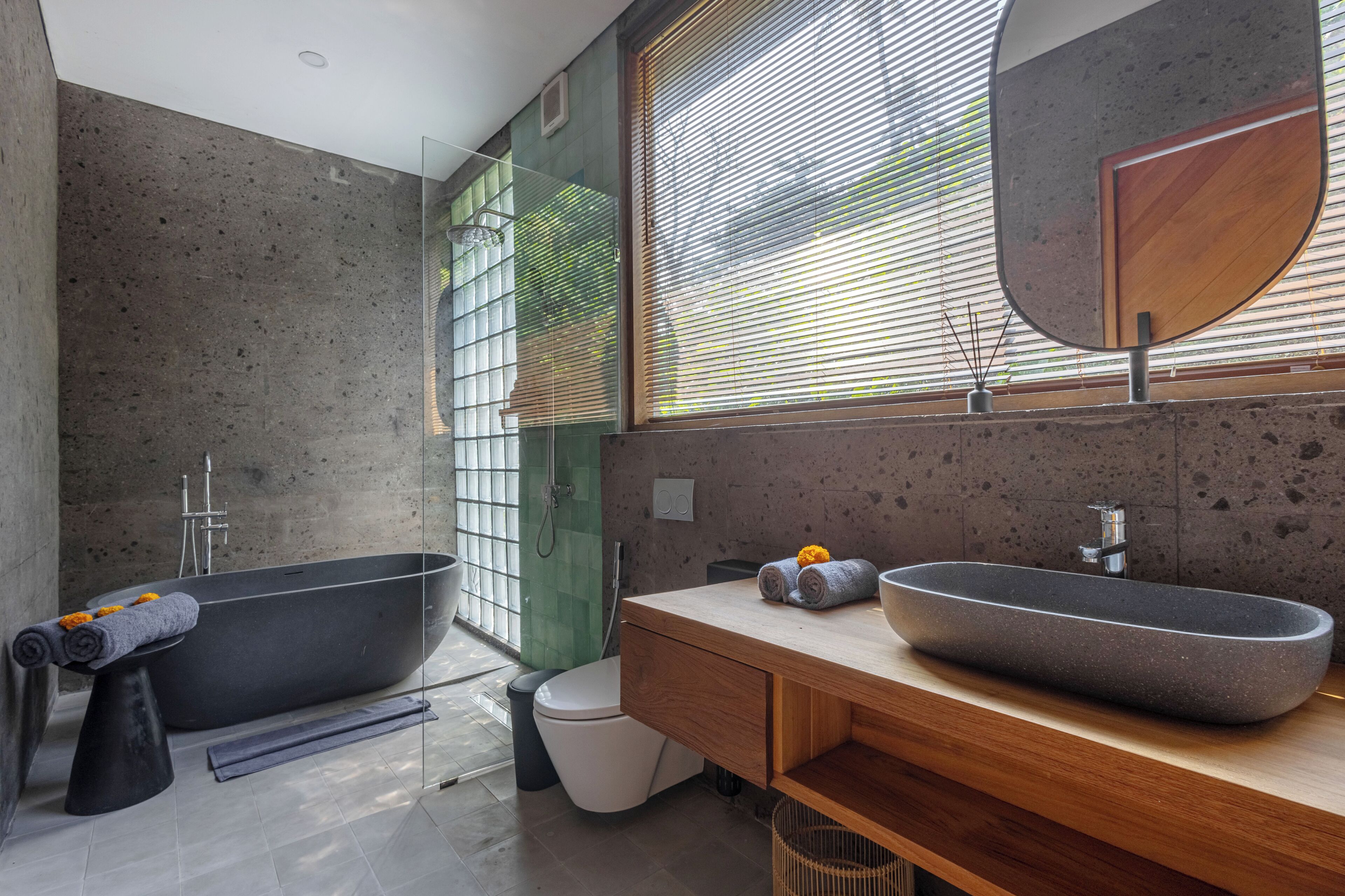 A modern bathroom with a freestanding bathtub, a large vessel sink, and a wooden vanity.