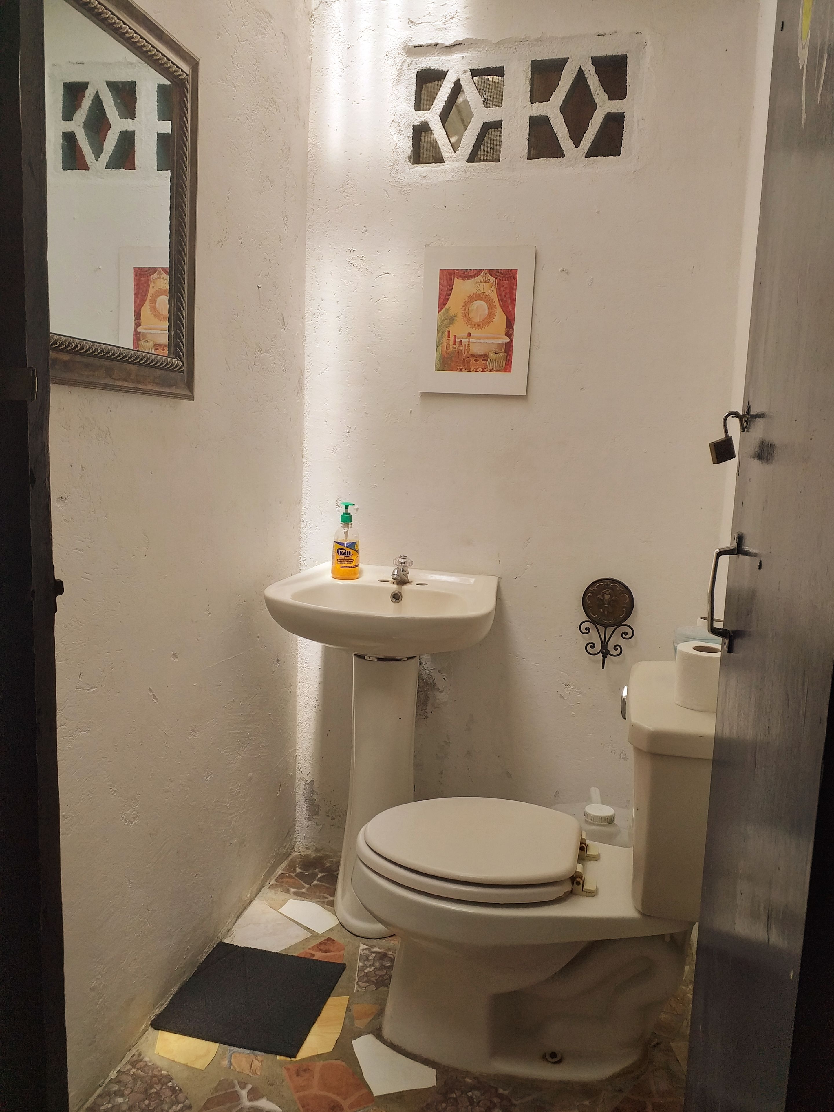 A small bathroom with a toilet, sink, and mirror.