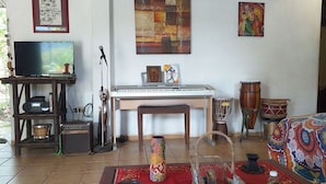 A living room with a television, a keyboard, a drum set, and a colorful rug. - La Casita de Don Daniel (El Valle de Anton)