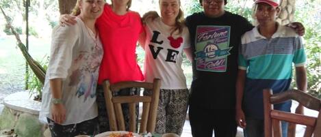 A group of people standing around a table with breakfast items.