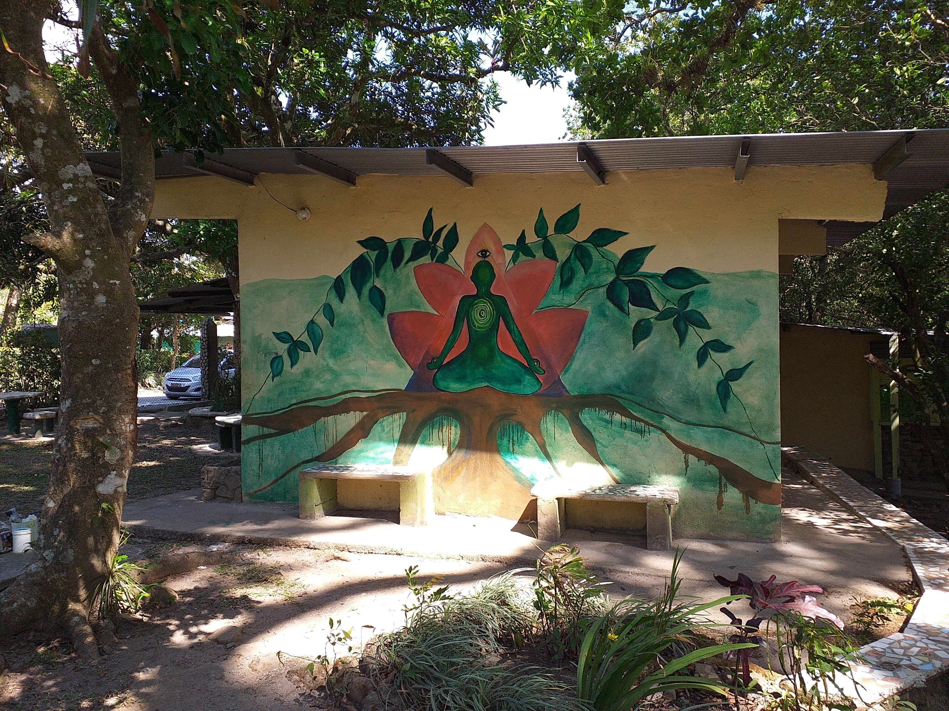 A mural of a meditating figure with a tree, benches, and a pathway.