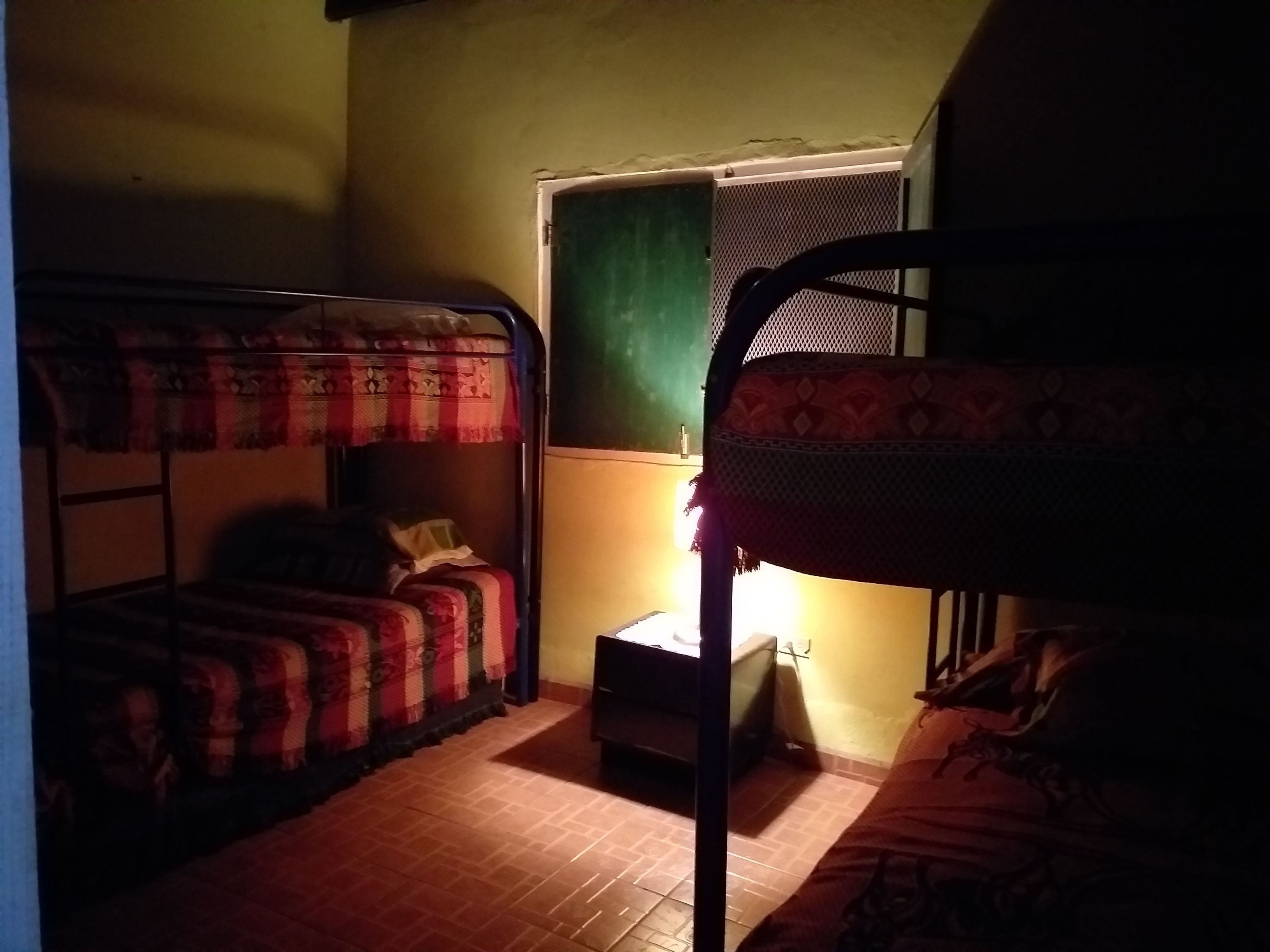 Une chambre de dortoir avec des lits superposés, une petite table et une fenêtre.