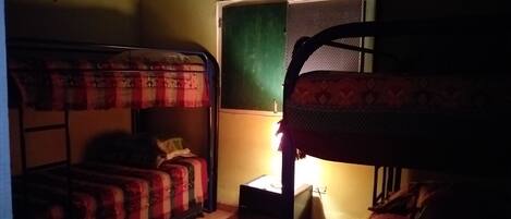 Un dormitorio con literas, una mesita pequeña y una ventana.