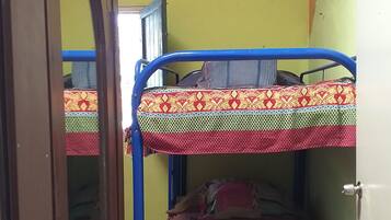 Una habitación con literas, una puerta de madera y una pared verde.