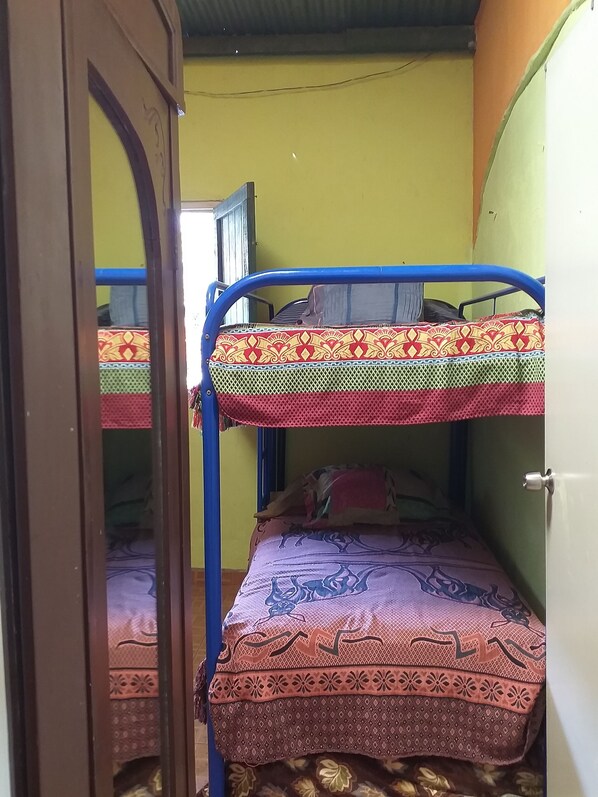 A room with bunk beds, a wooden door, and a green wall.