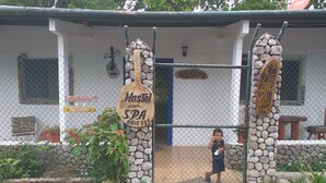 A hostel with a stone archway, a sign for a hostel and spa, and a child standing in the doorway. - La Casita de Don Daniel (El Valle de Anton)