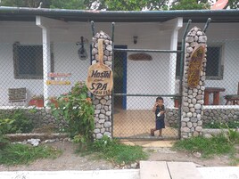 Un hostal con un arco de piedra, un cartel que indica hostal y spa, y un niño de pie en la entrada.