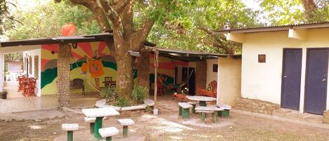 A courtyard with a large tree, outdoor seating, and a colorful mural.