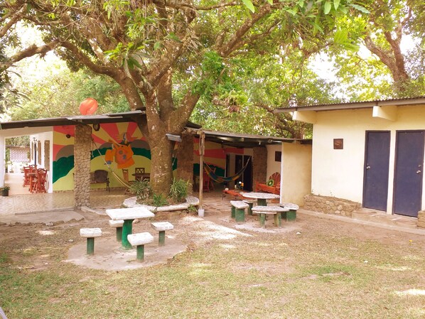 A courtyard with a large tree, outdoor seating, and a colorful mural.