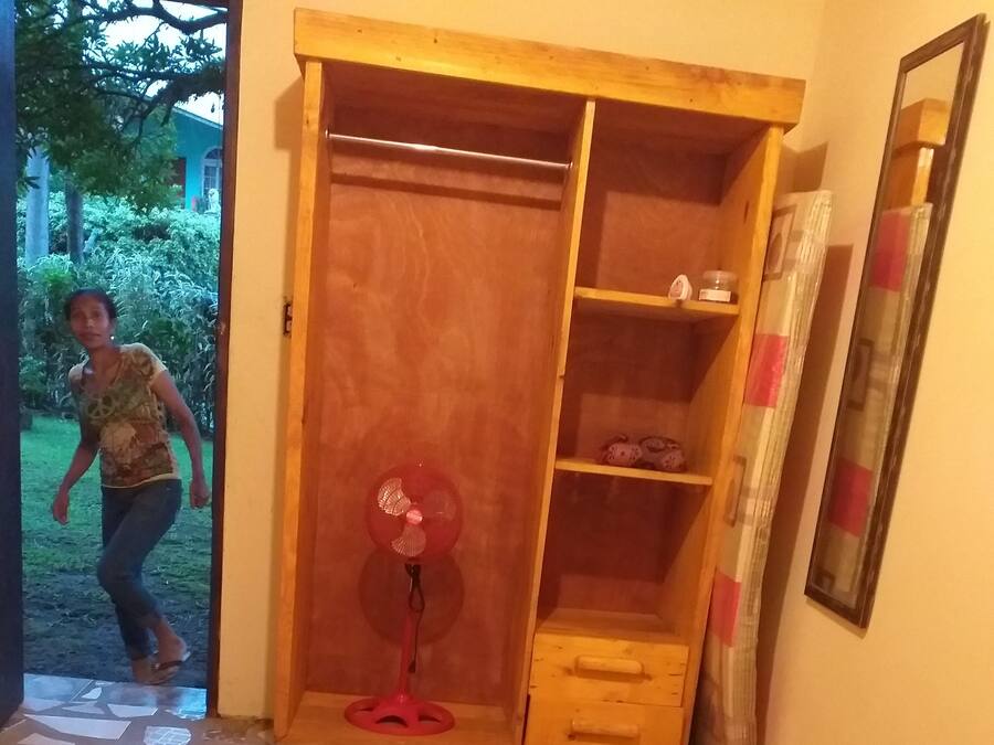 Una camera da letto con un'armadio in legno, una ventola a piantana e un letto con copripiumino a motivi floreali.