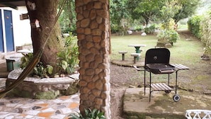A patio area with a stone pillar, a grill, and a tiled floor. - La Casita de Don Daniel (El Valle de Anton)